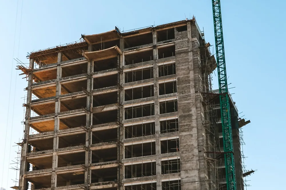 Edifício em construção com estrutura de concreto e grua