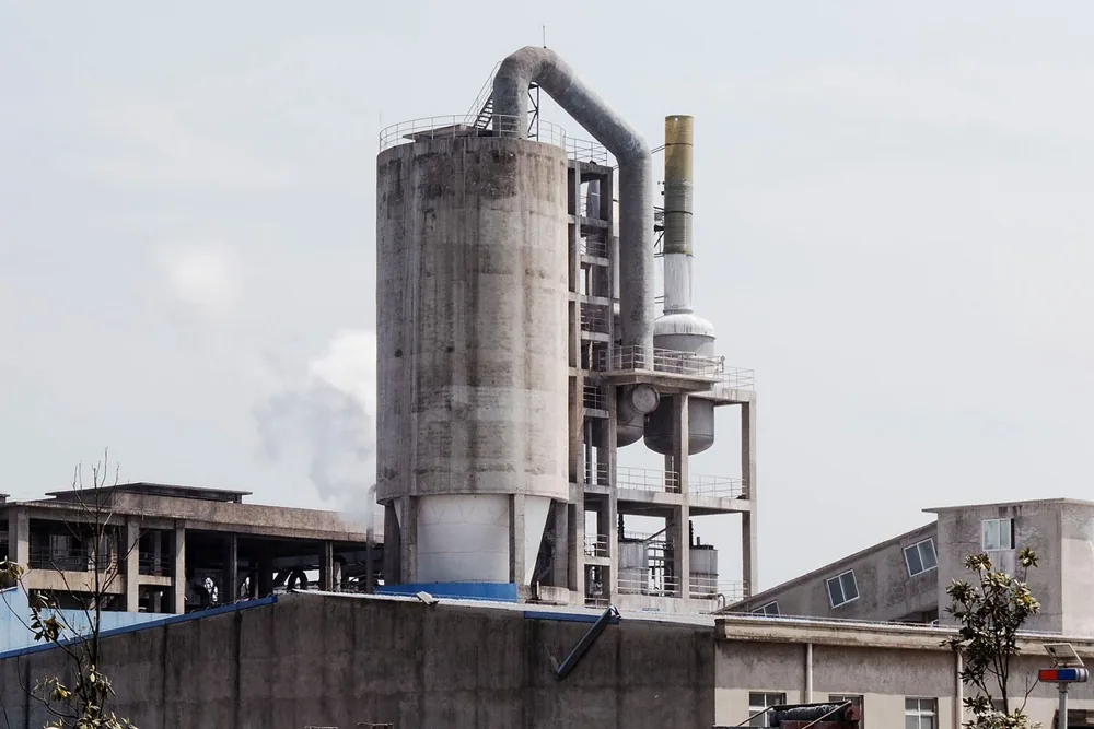 Fábrica em operação vista de fora, com silos e vapor